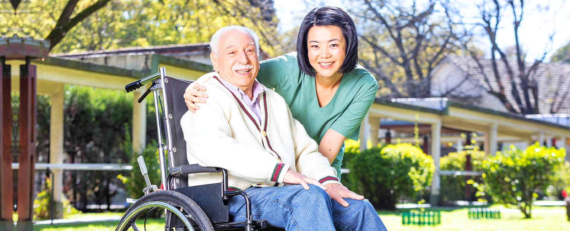 caregiver and elder man in a wheelchair smiling